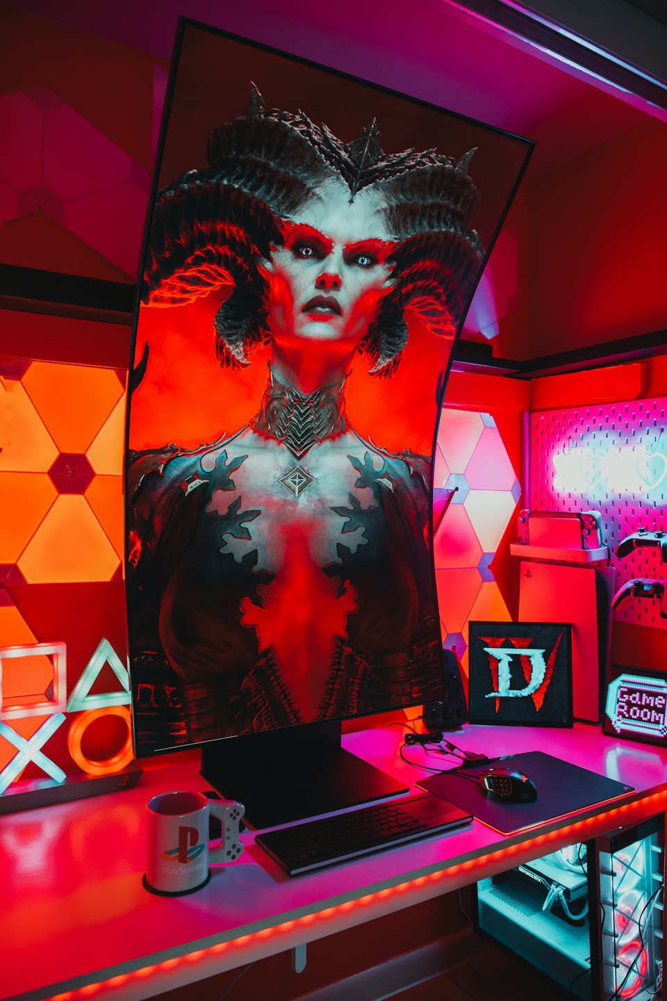 Gaming desk with curved monitor, keyboard, and PlayStation symbols.
