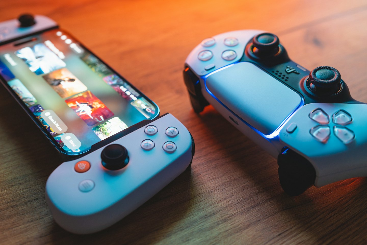 A smartphone and gaming controller resting on a wooden surface.