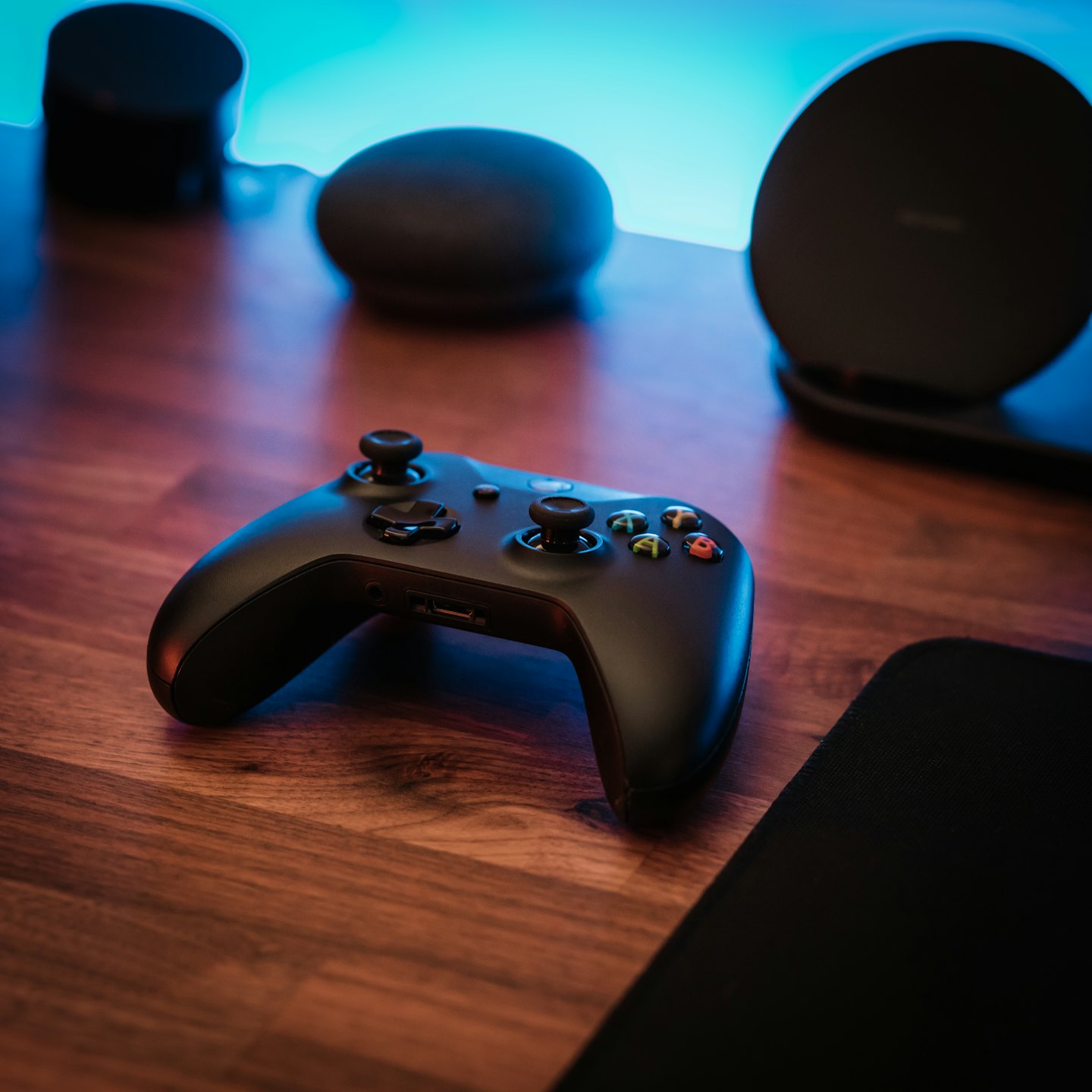 Video game controller on a wooden desk with colorful buttons.
