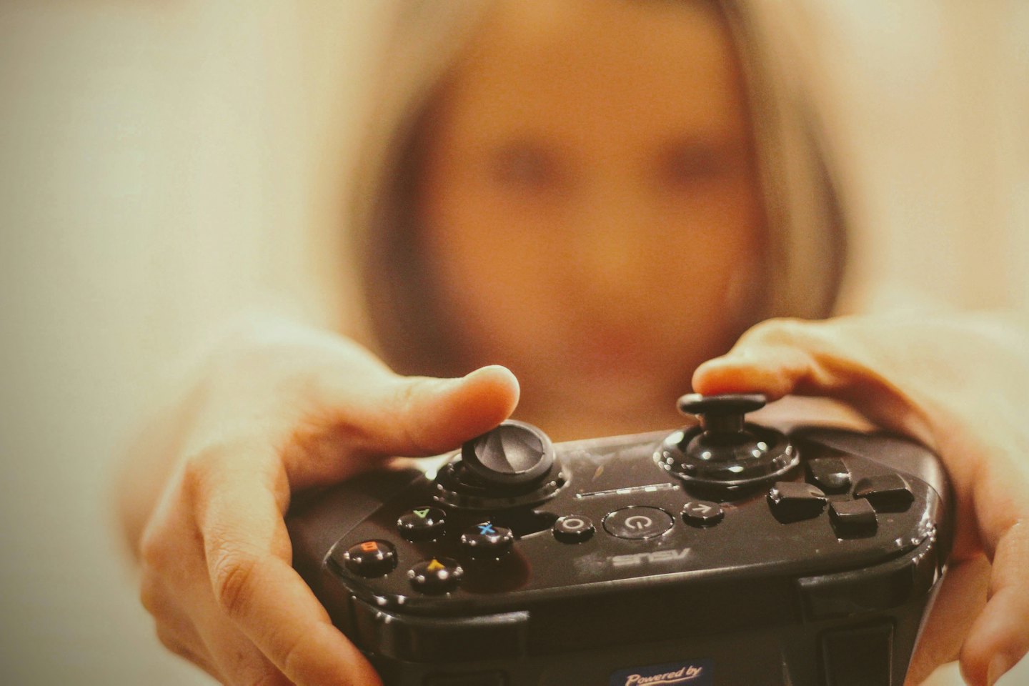 Hands holding a black game controller while playing a video game.