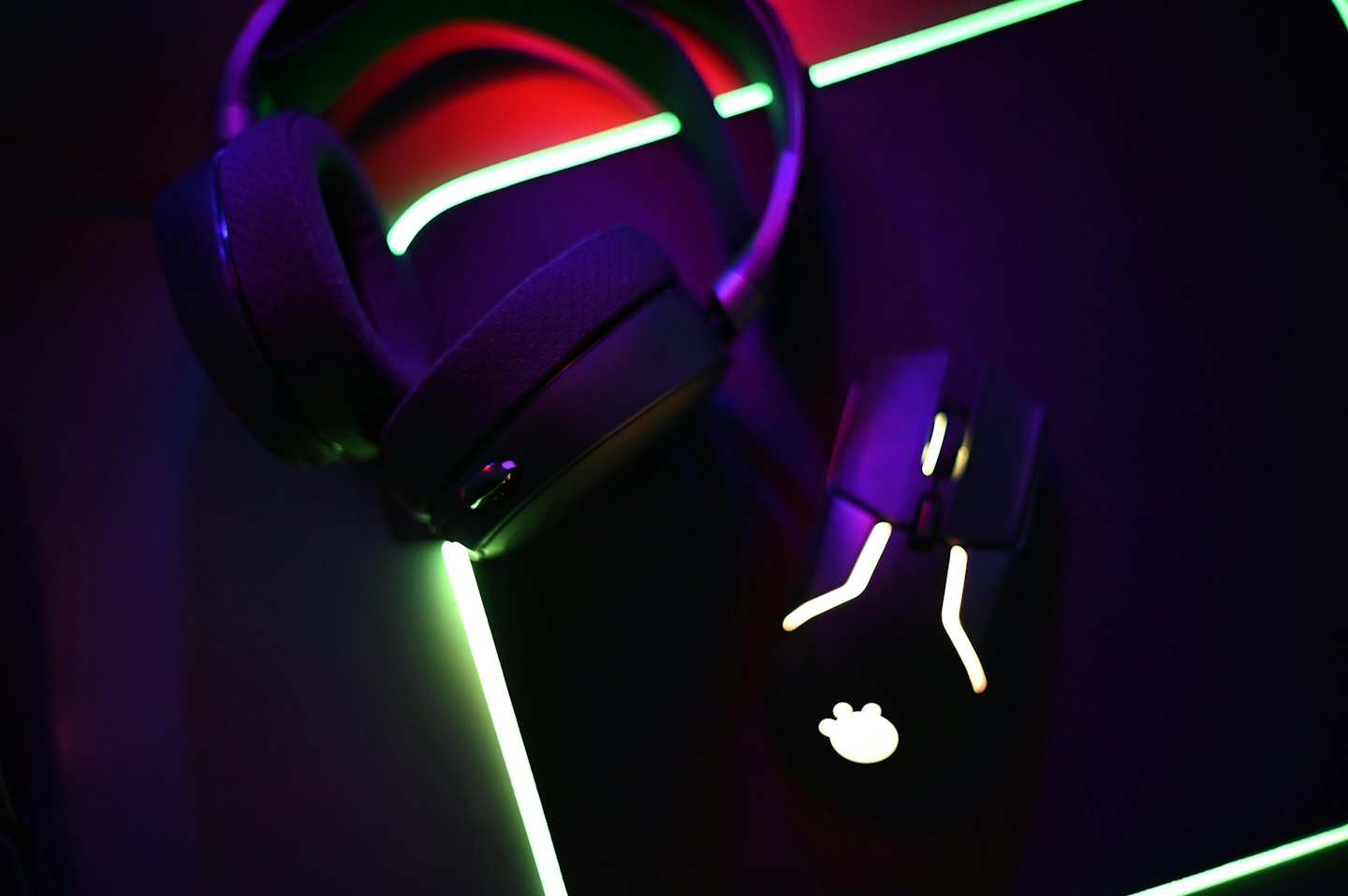 Black gaming headphones and mouse rest on a dark surface.