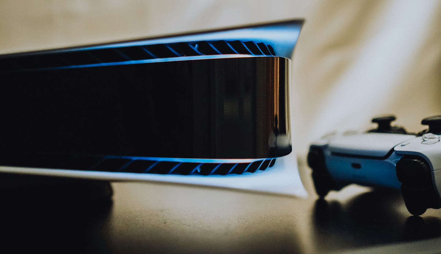 Modern video game console with blue light and controller.