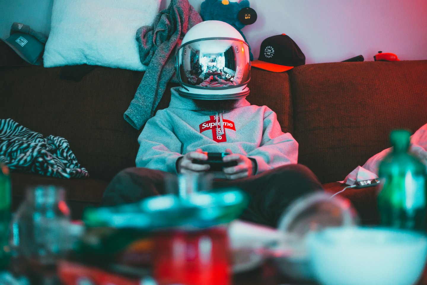 Person wearing an astronaut helmet plays video games on a couch.